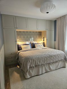 a large bed sitting in the middle of a bedroom next to a wall mounted cabinet