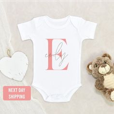 a baby's first birthday outfit with a teddy bear next to it and a heart