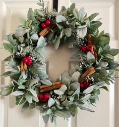 a wreath is hanging on the door with red berries and greenery in front of it