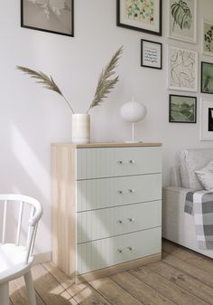 a room with white furniture and pictures on the wall, including a dresser or chest of drawers