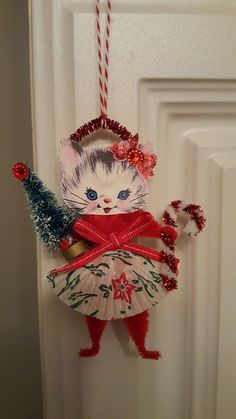 a cat ornament hanging on the door with a christmas tree in its hand