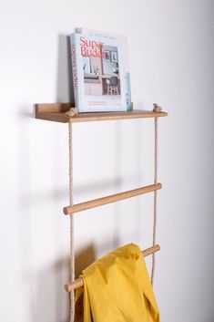 a book shelf with two books and a yellow bag on it next to a white wall