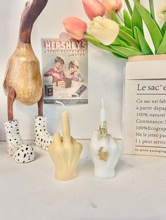 three small ceramic figurines sitting on top of a table next to a vase with tulips