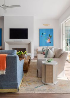 a living room filled with furniture and a flat screen tv mounted on the wall above a fireplace