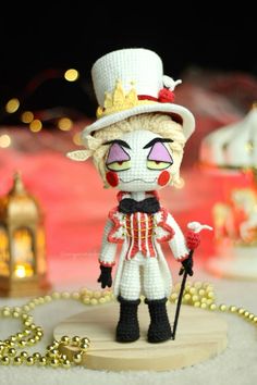 a crocheted doll is standing on a table with beads and lights in the background