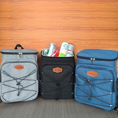 three cooler bags sitting next to each other in front of a wooden wall