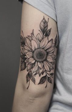 a woman's arm with a sunflower and leaves tattoo on the left arm