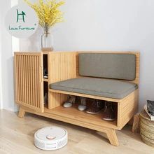 a room with a wooden bench and some shoes on the floor next to a robot vacuum