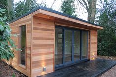 a small wooden building sitting on top of a wooden deck next to trees and bushes