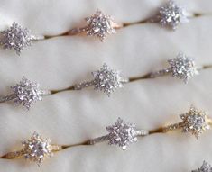 five different types of diamond rings on a white cloth with some gold and silver colors