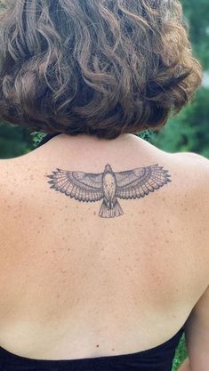 the back of a woman's shoulder with a bird tattoo on her upper arm