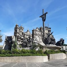 a statue of jesus on the cross in front of a building with statues around it