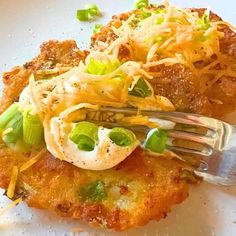 a white plate topped with food covered in cheese and veggies next to a fork