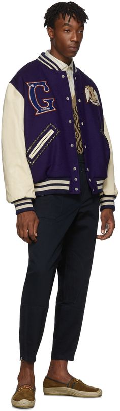 Long sleeve panelled wool and lambskin bomber jacket in purple and off-white. Tonal rib knit wool stand collar, cuffs, and hem. Press-stud closure at front. Multicolor embroidered logo patches at chest. Welt pockets with pyramid studs at waist. Embroidered text and graphic in off-white, black, red, and blue at back. Buttoned patch pocket at interior. Quilted satin lining in pink. Supplier color: Blue Gucci For Men, Embroidered Text, Gucci Outfits, Buy Gucci, Luxury Streetwear, Welt Pockets, Pyramid, Stand Collar, Patch Logo