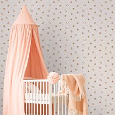 a baby crib with a pink canopy and stars on the wall next to it