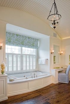 a large bathroom with a tub, sink and window in the center is shown here