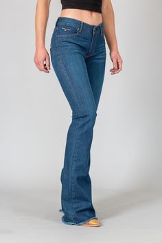 Our bestselling Lola with a new look. The mid-rise, flare leg jean in our innovative tri-blend denim in a deep blue wash with light hand-sanding, raw hems, and pink and brown thread rear pocket logos. Fabric: 93% Cotton | 6% Polyester | 1% Elastine Fit: Mid Rise, Trouser Fit, Wide Flare Leg Details: Light hand-sanding, with pink and brown threaded rear pocket logos and raw hems. Construction: 11.25 Oz. Denim Our jeans have the longevity and durability you demand because we only source ring-spun Kimes Ranch, Western Wear Outfits, Western Store, Cowgirl Western, Raw Hem Jeans, Hem Jeans, Flare Leg Jeans, Western Wear, Jeans Style