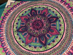 an intricately colored circular design is shown on the tablecloth, which has been made with