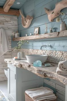 a bathroom with blue walls and stone counter tops, along with white towels on the shelves