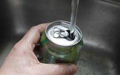 a hand holding a can of soda in a sink