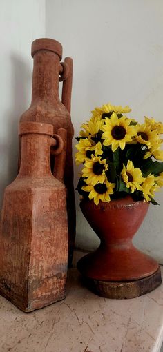 two vases with yellow flowers in them sitting on a table next to each other