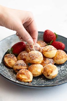 a person dipping sugar on some pastries with strawberries