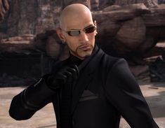 a bald man in a black suit and sunglasses pointing to the side with his hand on his hip