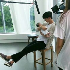 a man sitting in a chair holding a baby next to a woman with headphones on