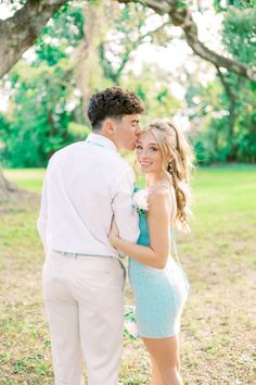 a man and woman standing next to each other under a tree