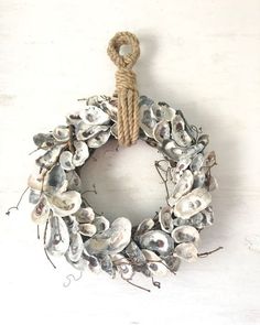 a wreath made out of seashells hanging from a rope on a white wall