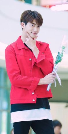 a young man in a red jacket is holding flowers