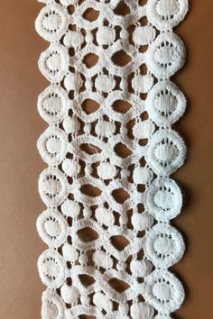 the crocheted doily is hanging on the wall in front of a brown background