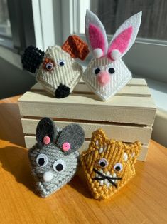 three knitted animal heads sitting on top of a wooden box next to a window