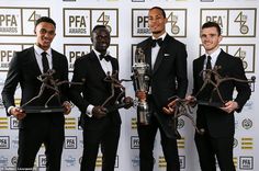 three men in suits holding trophies and posing for the camera