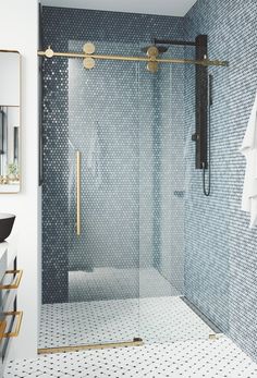 a bathroom with a glass shower door and white tile flooring, along with a gold framed mirror on the wall