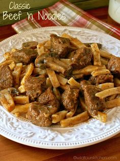 a white plate topped with pasta covered in beef and sauce next to a glass of milk