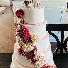 a wedding cake decorated with flowers and two dogs on top is sitting on a table