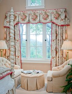 a living room filled with furniture next to a window covered in curtains and drapes