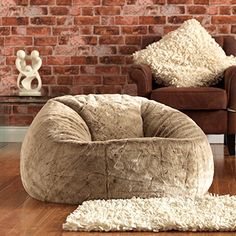 a large bean bag chair sitting on top of a wooden floor next to a brick wall