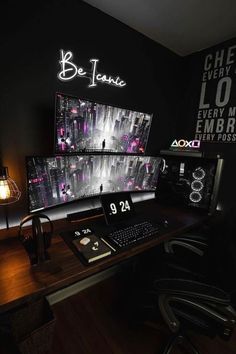 a computer desk topped with two monitors and a keyboard next to a light on the wall