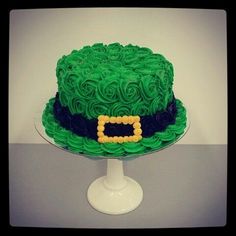 a cake with green frosting and a batman symbol on top is sitting on a pedestal