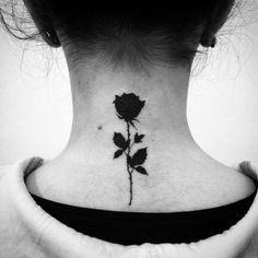 a woman's neck with a rose tattoo on it