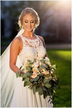 a woman in a wedding dress holding a bridal bouquet and smiling at the camera