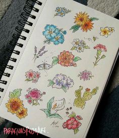 an open notebook with drawings of flowers and butterflies on the pages, sitting on carpet