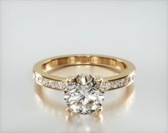 a gold engagement ring with diamonds on the band and a center stone in the middle