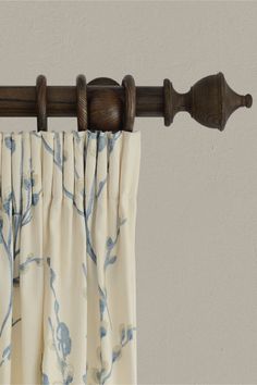 the curtain is pulled back by a wooden rod and has blue flowered curtains on it