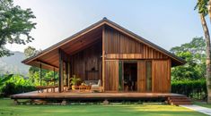 a wooden house sitting on top of a lush green field