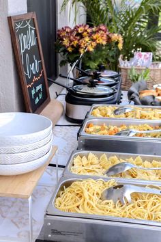 a buffet table filled with lots of different types of pasta and other foods on trays