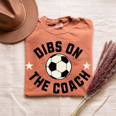 a t - shirt that says dubs on the coach with a soccer ball and hat next to it