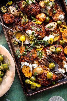 a pan filled with chicken, olives and feta cheese on top of a table